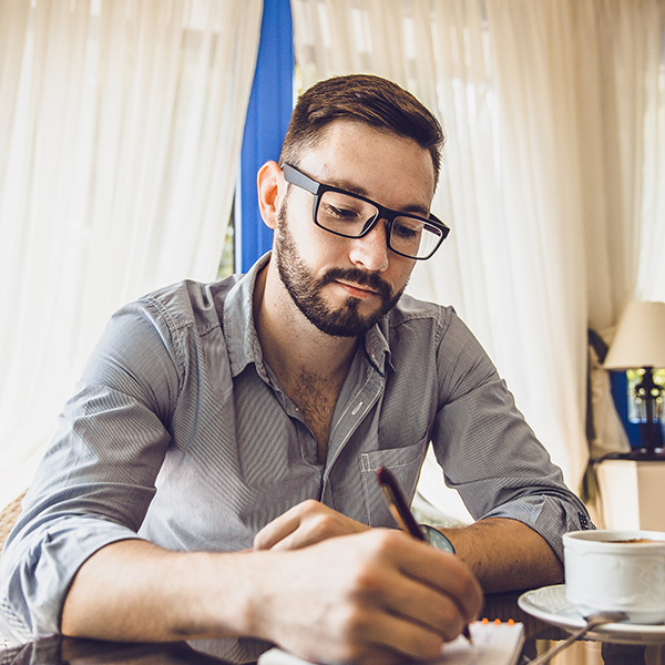 Young man writing at a desk for individual therapy in Louisana